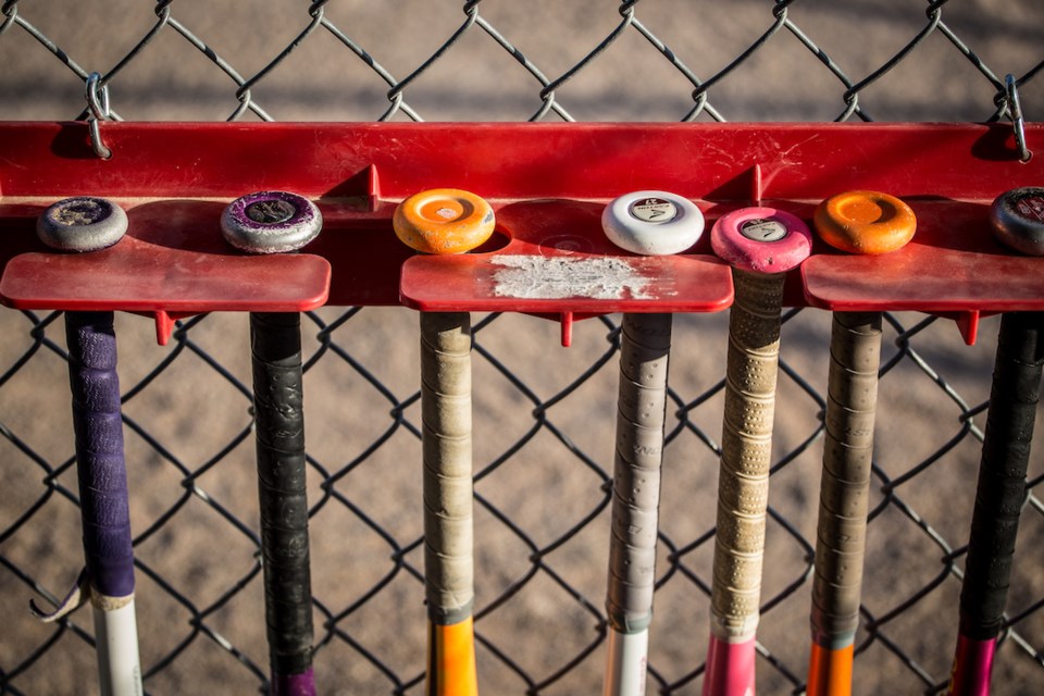A row of softball bats hang in the dugout.