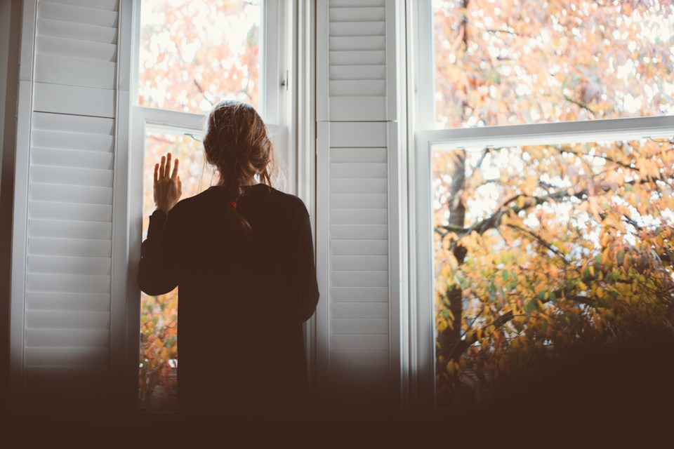 A woman with her hand on the glass, waving