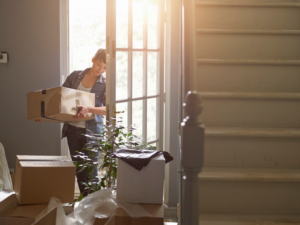 And woman carrying a packing box into her new home