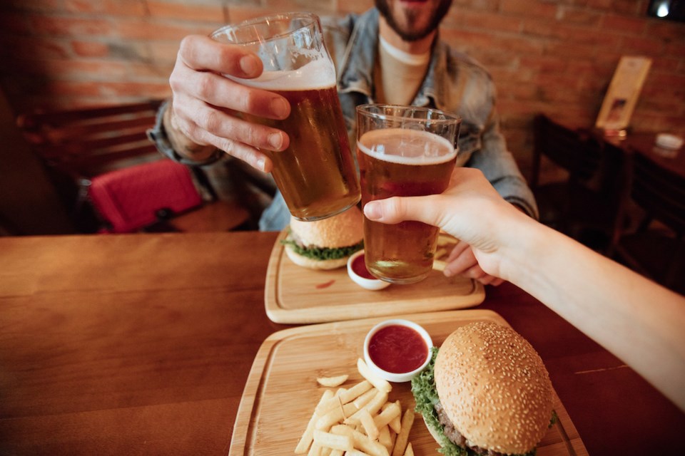 Clinking beer glasses with burgers on plates