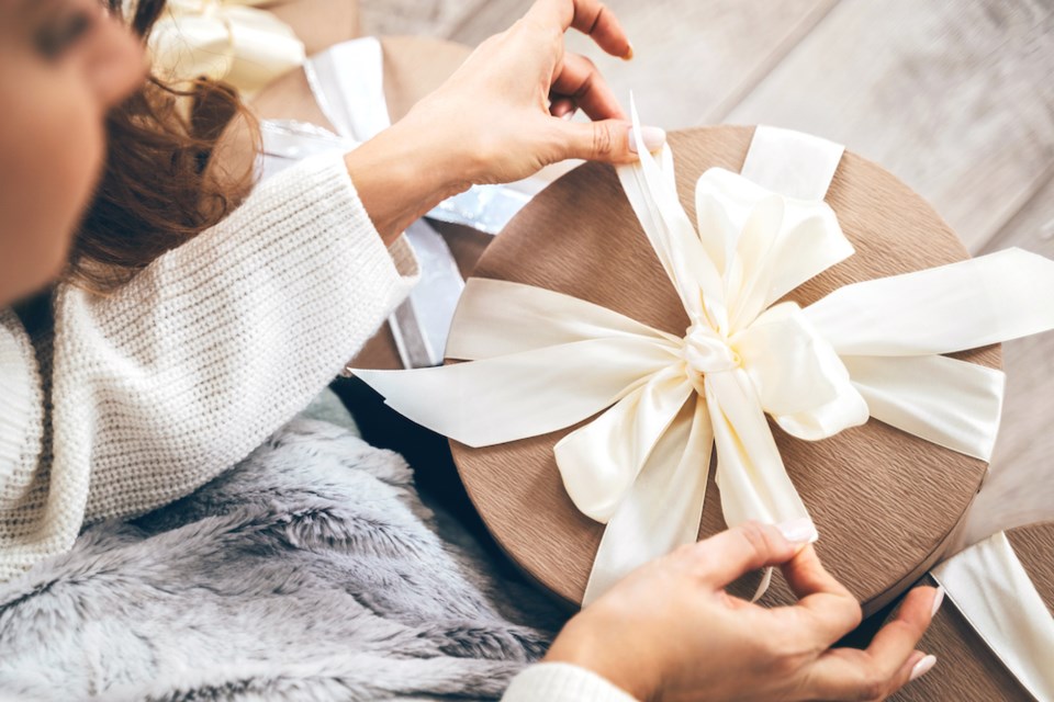 close-up-of-a-woman-wrapping-gifts-and-tying-a-pastel-ribbon-bow