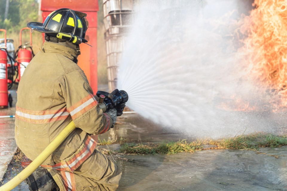 Firefighters spraying high pressure water to stop fire burning point.