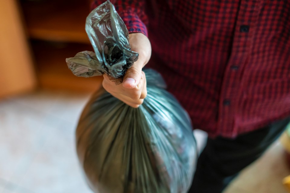 hand holding a trash garbage bag at home to take it away