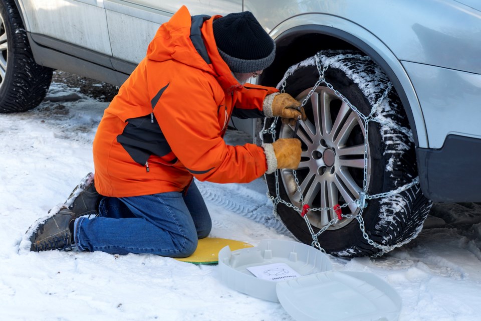 Man attaching chains to car tire