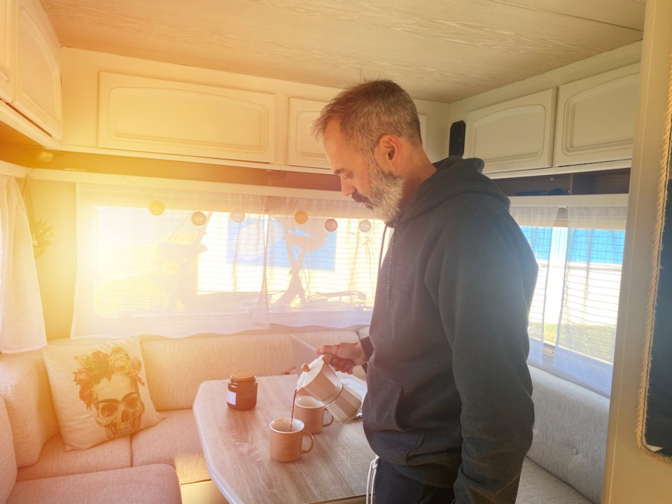 Man serving coffee on dining table inside a camper vehicle, RV.. 