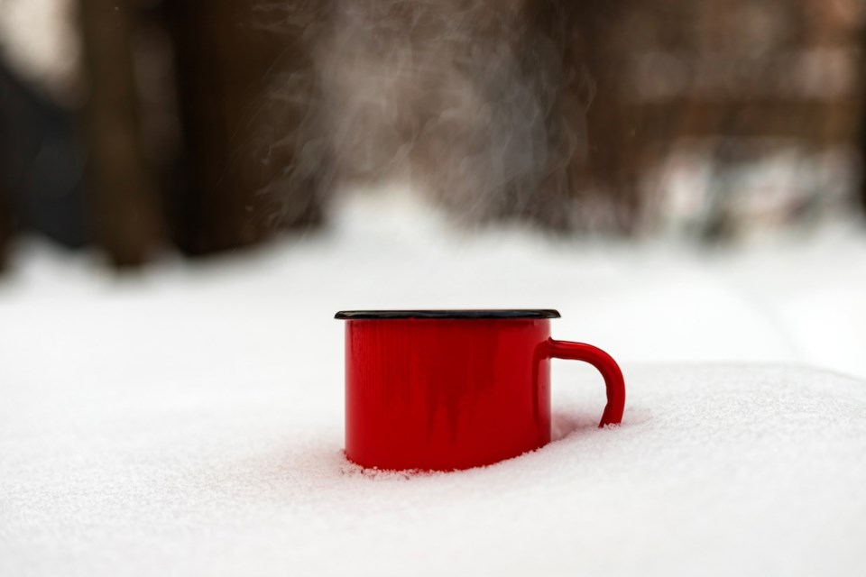 red-metal-mug-with-hot-drink-standing-in-snowy-forest