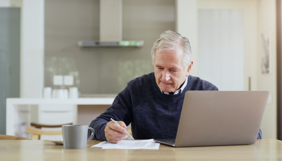 Shot of a senior man using a laptop while going over his bills and finances at home