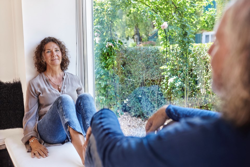 Two people looking at one another beside a picture window