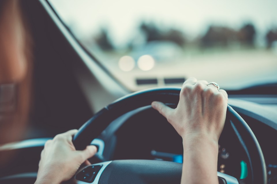 Woman with hands on steering wheel