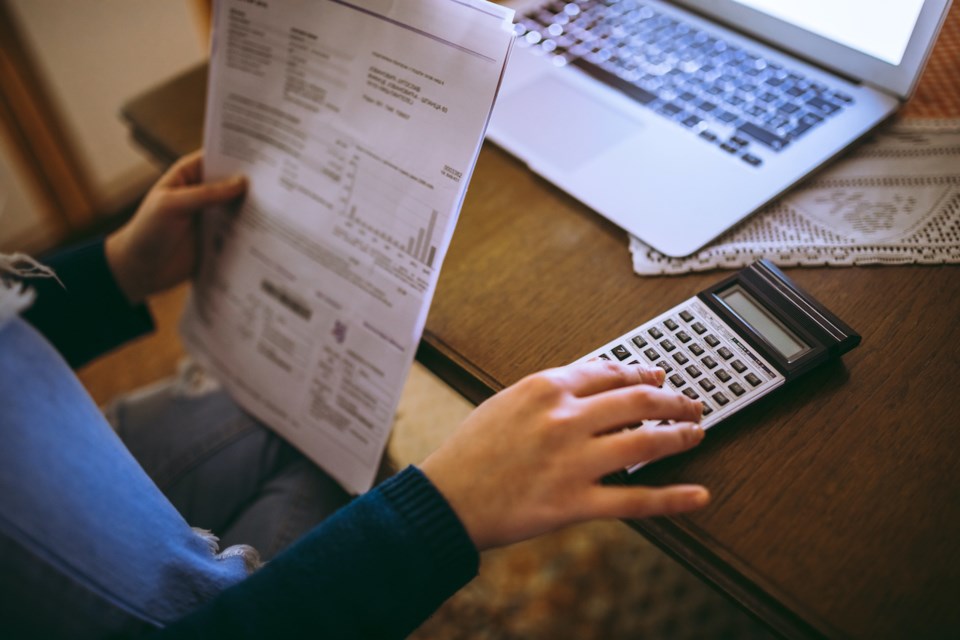 Young woman reading her bill papers and using calculator