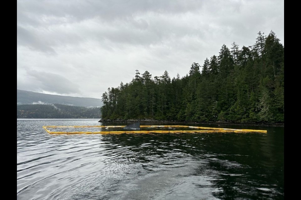 A containment boom surrounds where the decommissioned former ferry the R.J. Breadner sank in Sechelt Inlet.