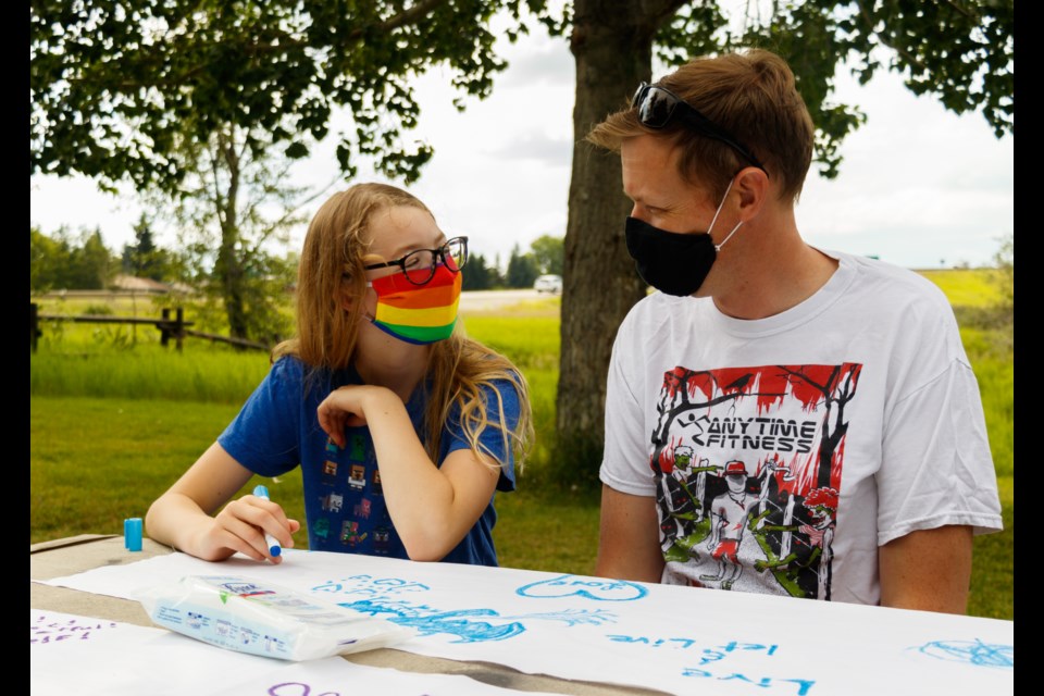 Shawn Caufield and daughter Rauri add their personal touch to the Kindred Cochrane Pride Societyâs flag at a family paint night event at the Cochrane Ranche on Wednesday (July 22). The flag will serve as banner for future Kindred celebrations. (Chelsea Kemp/The Cochrane Eagle)