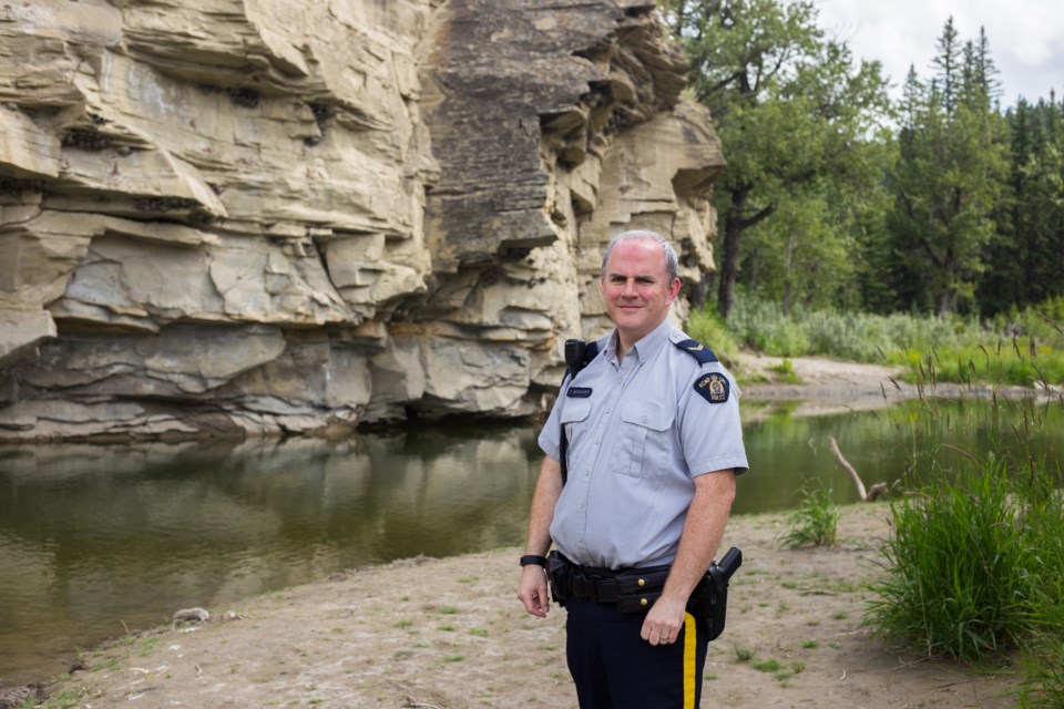 Cochrane RCMP Cpl. Troy Savinkoff stands in a popular trespassing area near Jumpingpound Creek on Friday (July 31). (Chelsea Kemp/The Cochrane Eagle)