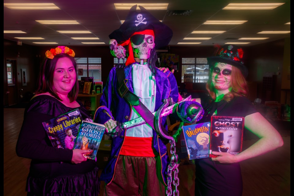 Community outreach and program librarians Jessie Pepin, left, and Andrea Johnston showcase haunted novels at the Cochrane Public Library on Monday (Oct. 26). (Chelsea Kemp/The Cochrane Eagle)