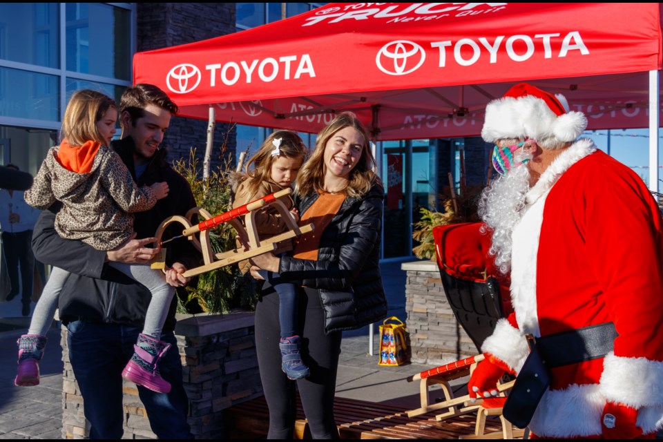 Santa delivers a children's sled donated by Cochrane Toyota to the Mitchell family Sunday (Dec. 20). (Chelsea Kemp/The Cochrane Eagle)