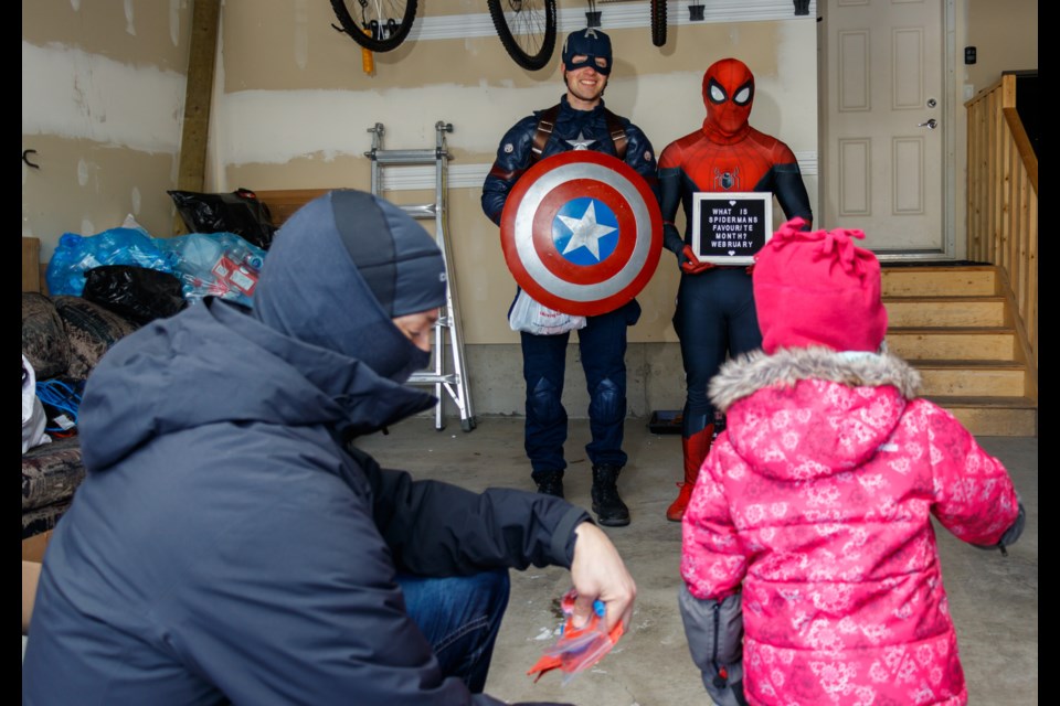 Captain America and Spider-Man deliver Valentine's Day greetings to Billy, 6, and Georgia, 3, on Sunday (Feb. 14). The curbside Valentine's Day festivities were made possible by the Wish I May Parties. (Chelsea Kemp/The Cochrane Eagle)