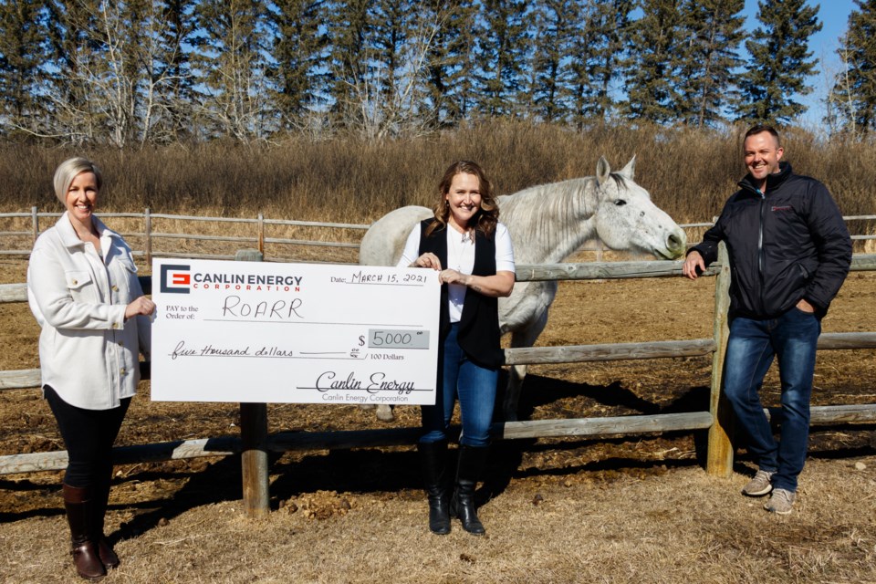 Canlin Energy operations administrator Kaili Dale, left, and Wildcat Hills district superintendent for Canlin Energy Tim Adams, right, present ROARR  executive director Janet Robinson with a $5,000 grant on Monday (March 15).( Chelsea Kemp/The Cochrane Eagle)