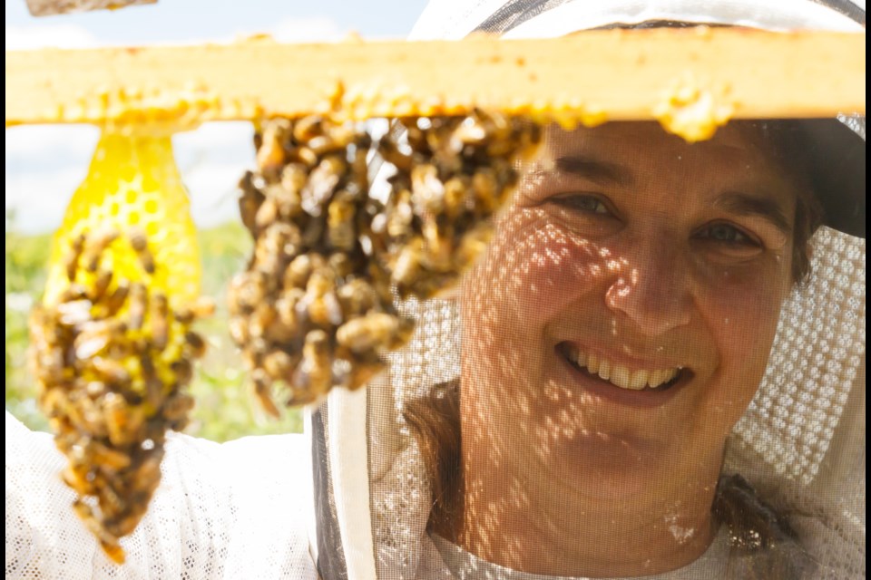 Beekeepers Gisele Hardock and Sydney Bradbury, 14, check on bees at Summit Hill Farms on Sunday (June 20). (Chelsea Kemp/The Cochrane Eagle)