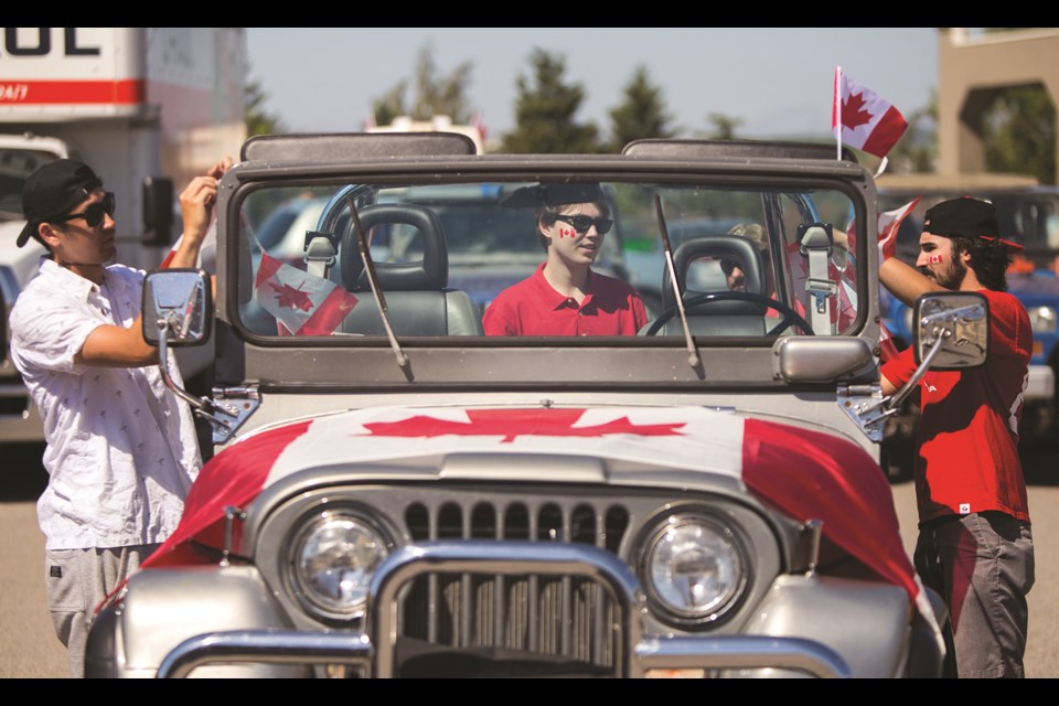 Nick Roberts, left, Zach Johnston and Daniel Skoric decorate their Jeep for the Canada Day parade organized by the Cochrane and Area Events Society on July 1, 2021. (Chelsea Kemp/The Cochrane Eagle)
