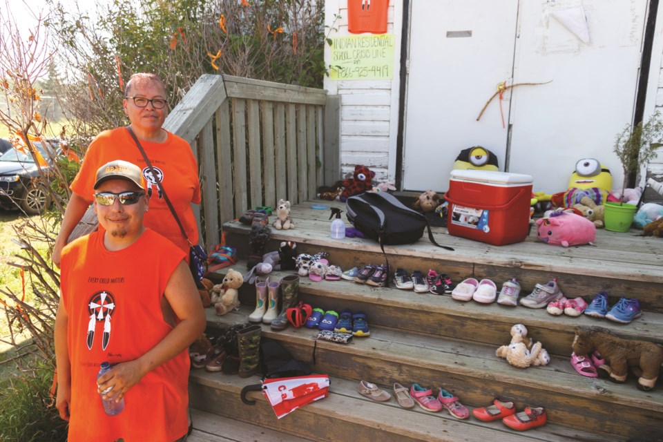 Eve Powder and Clement Holloway lead a march honouring children found in unmarked graves at former Residential Schools on Thursday (July 1). The walk began at the Chiniki Gas Station in Stoney Nakoda First Nation and ended at the Morley United Church. (Chelsea Kemp/The Cochrane Eagle)