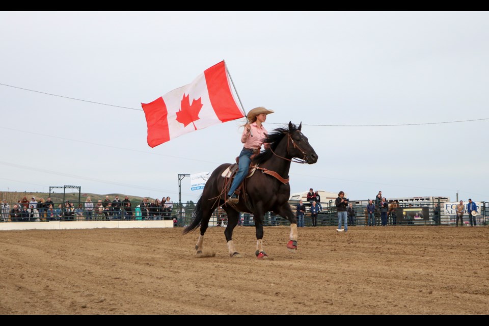 A rider carrying the Canada flag opens the ceremonies of the 20th annual Cochrane Classic Bull Riding on Saturday (Aug. 21). (Jessica Lee/The Cochrane Eagle)