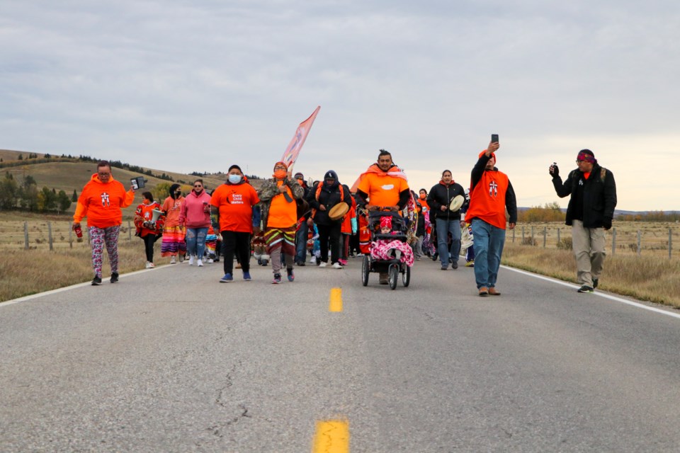 People walk three kilometres from the McDougall Memorial United Church to the Morley United Church to raise awareness for residential school survivors and non-survivors at the first annual National Day for Truth and Reconciliation on Sept. 30, 2021. (Jessica Lee/The Cochrane Eagle)