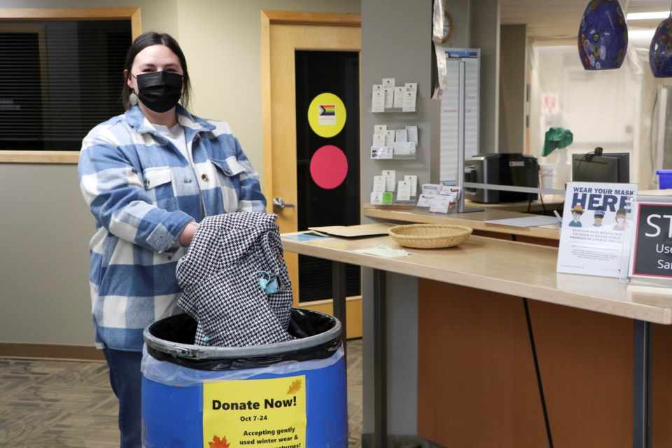 Family Resources Network support worker Tessa Davidson puts a jacket into a donation bin at the Cochrane Family and Community Support Services office on Friday, Oct. 22. (Jessica Lee/The Cochrane Eagle)