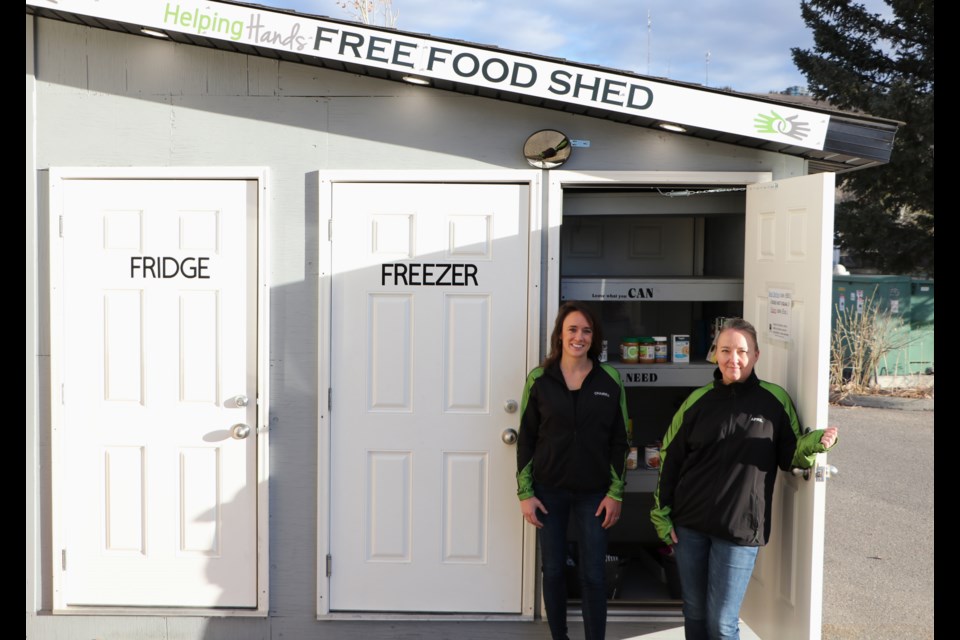 Helping Hands executive director Chairra Nicolle, left, and food security programs manager April Baird visit the free food shed at St. Andrew's United Church to check stock levels and organize items on Nov. 5. Helping Hands will soon be opening a second free food shed at Bow Valley Baptist Church. (Jessica Lee/The Cochrane Eagle)