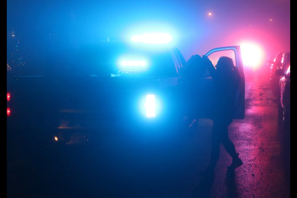 A volunteer of the First Responders Parade puts a bag full of donated items into the back of an RCMP vehicle on a foggy night in Sunset Ridge Nov. 15. (Jessica Lee/The Cochrane Eagle)