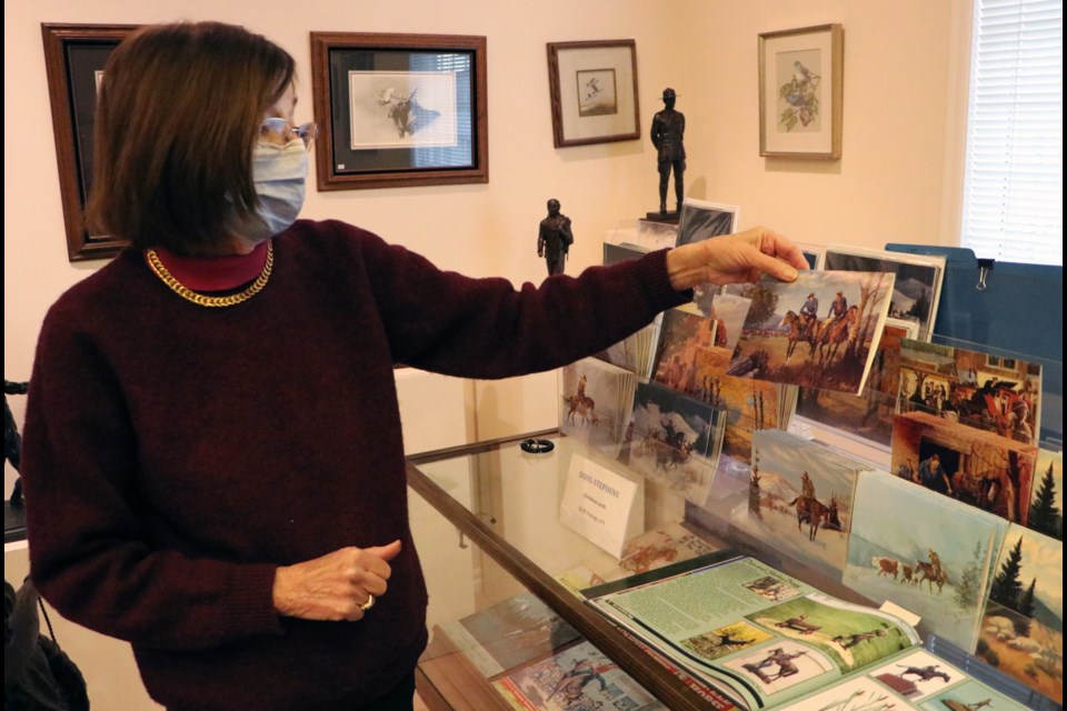 Shirley Begg, owner of Studio West Gallery & Bronze Foundry holds up an art card at the gallery Nov. 18 as an example of their contribution to the Cochrane Loves Local gift box. The print is from an original painting by Begg's late father, renowned western artist Doug Stephens. (Jessica Lee/The Cochrane Eagle)