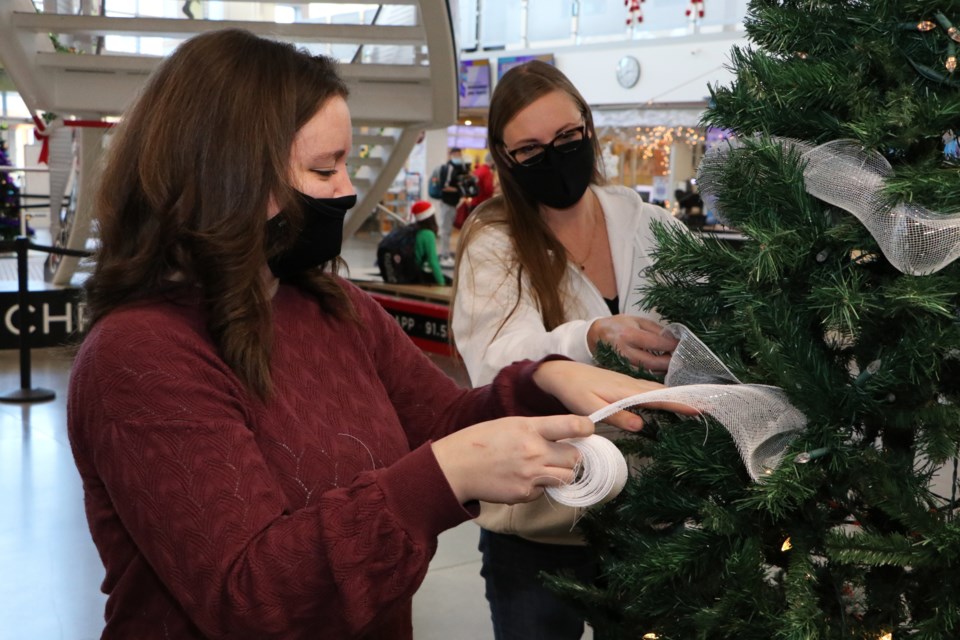 Kourtney Cameron, left, and Cherie Haynes with North Star Ford decorate their company sponsored tree. Organizations are able to sponsor a tree to decorate at SLSFSC for $150 by contacting the Cochrane Lioness Club. (Jessica Lee/The Cochrane Eagle)