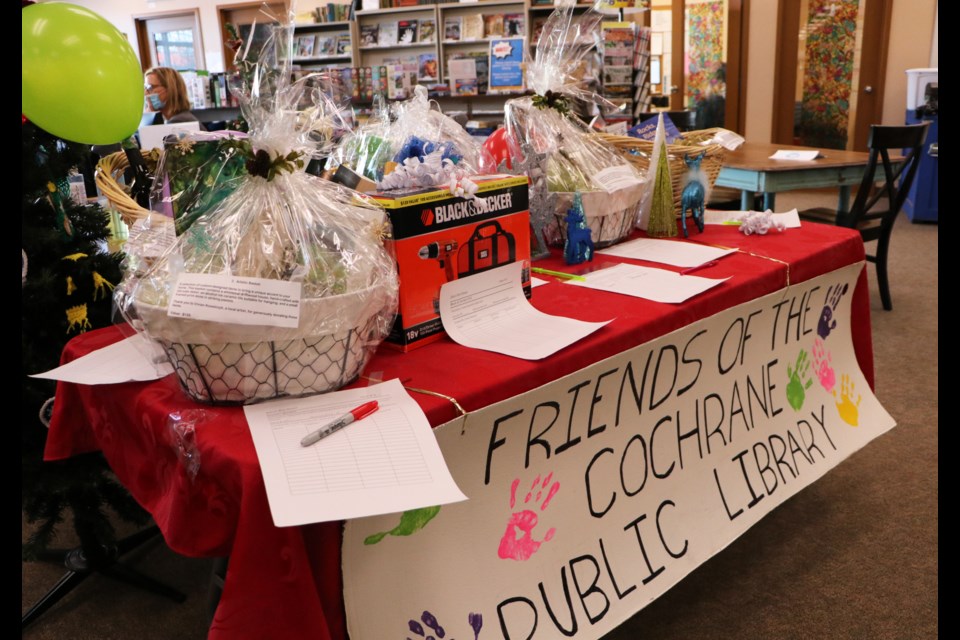 A table with gift baskets and items available through the Friends of the Public Library's silent auction is viewable at the Cochrane Public Library. The auction will run until Dec. 21. (Jessica Lee/The Cochrane Eagle)