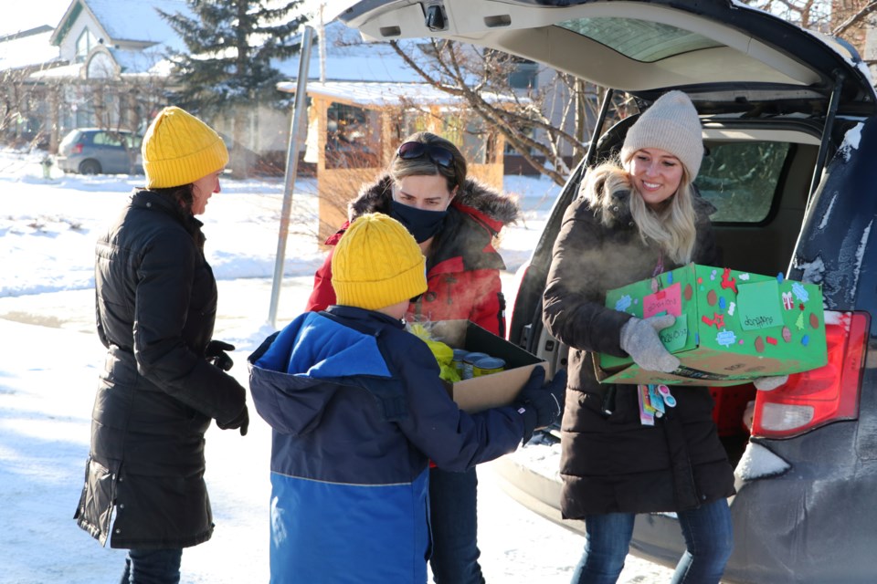 Elizabeth Barrett Elementary School kindergarten teachers Jeanne Duvette, middle, and Lauren Southwick, right, unload food donations for the Helping Hands free food shed Dec. 17 from their classes' collective food drive this week. The donation boxes were decorated by the kindergarten students. (Jessica Lee/The Cochrane Eagle)