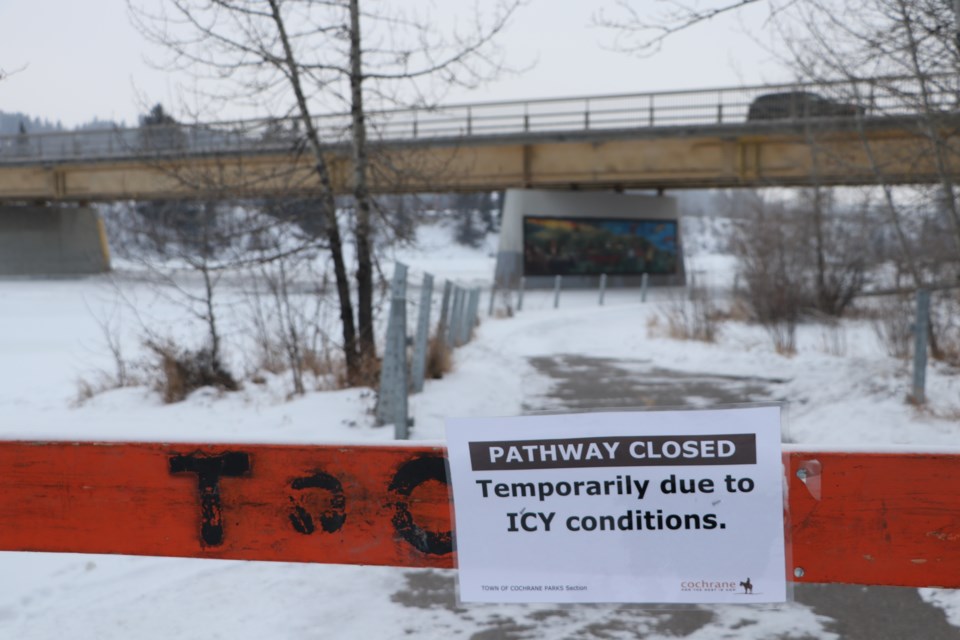 A sign marks the closure of a pathway in Riverfront Park due to overland flooding from the Bow River, beneath the Highway 22 bridge. (Jessica Lee/The Cochrane Eagle)
