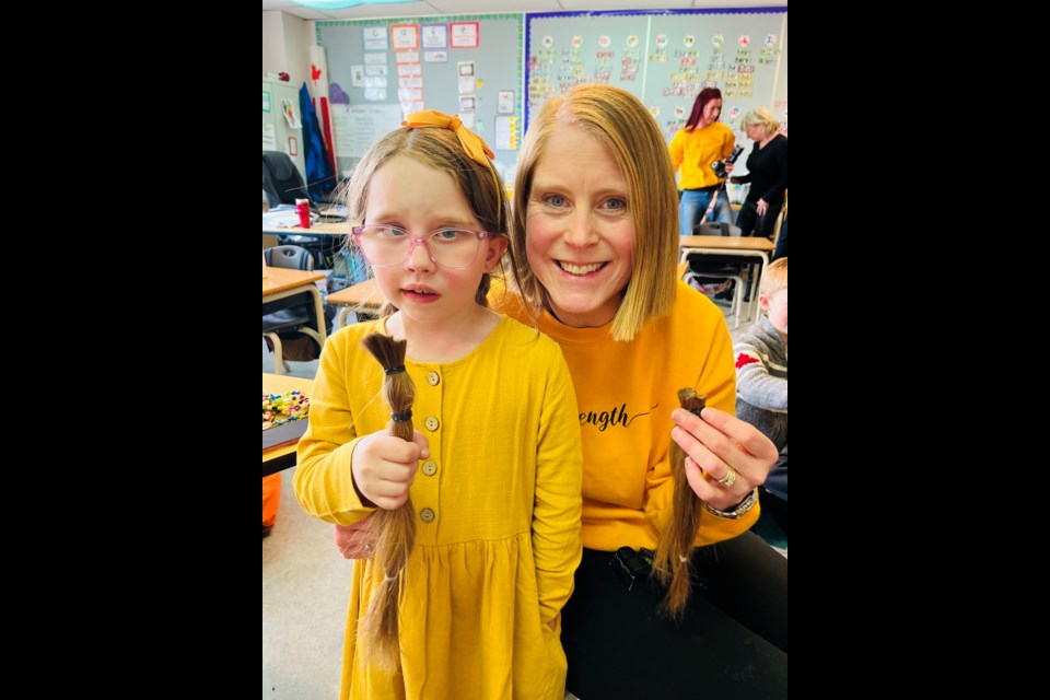 'Share the Love' fundraiser organizers Ella, 7, and teacher Jessica Powers show off the 12 inches of hair snipped in a hair-cutting ceremony on March 14 at Glenbow Elementary School. 
