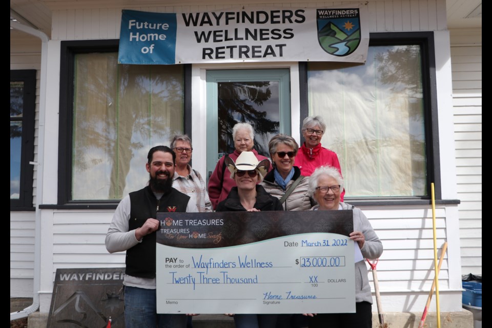 Wayfinders Wellness Retreat vice-president Chris Reader and board member Steph accept a donation from Cochrane Home Treasures chair Barb Primeau and board members Linda LeClaire, back left, Lorna O'Shea, Paola Dottor-Cena and Allison Robb on April 4. (Jessica Lee/The Cochrane Eagle)