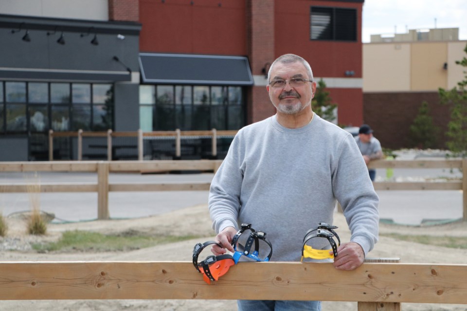 Georges-Andre Tambay holds a sample of Treksteppers at the LaunchPad bike park in Cochrane May 23. The shoe accessory was invented by Tambay to help hikers with sore joints descend slopes. (Jessica Lee/The Cochrane Eagle)