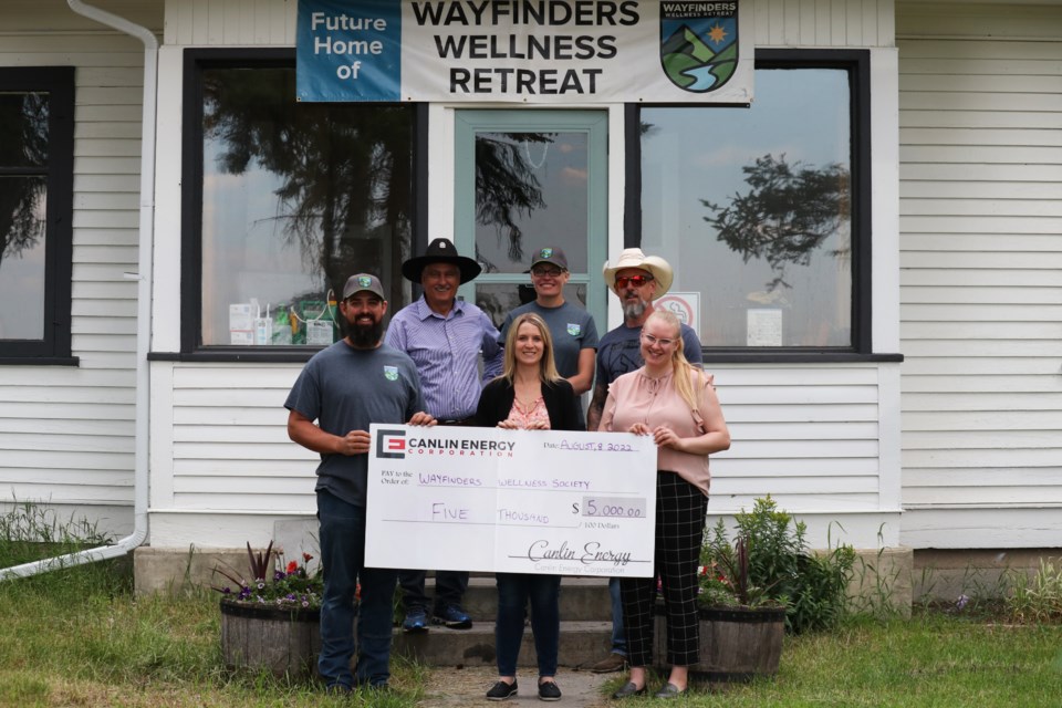Wayfinders Wellness Retreat president Chris Reader, left, board member Ray Smith, officer manager and administrator Steph D. and founder Paul Wagman, accept a $5,000 donation from Canlin Energy operations support technician Janelle Dubord and operations support summer student Breanna Van Ee on Aug. 2. (Jessica Lee/Cochrane Eagle)