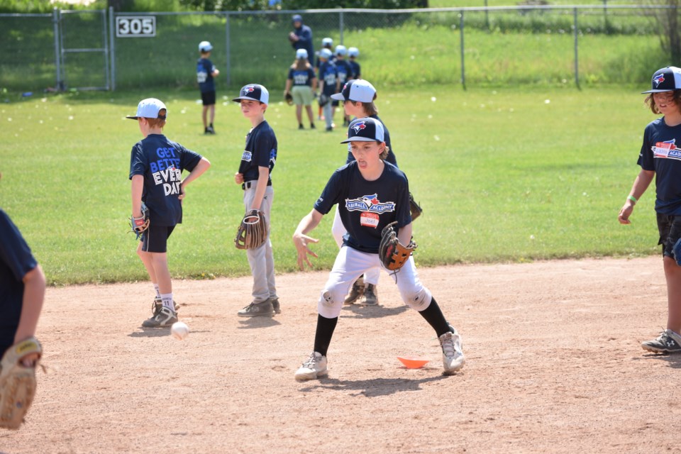 A kid practicing catching a ground ball at the Blue Jays Baseball Academy clinic at the Rodeo Grounds South Diamond