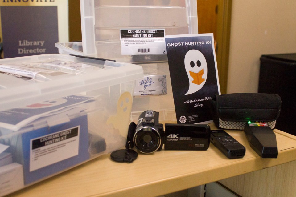 The contents of the ghost hunting kits provided by the Cochrane Public Library. It includes a camera, voice recorder, and an EMF reader.