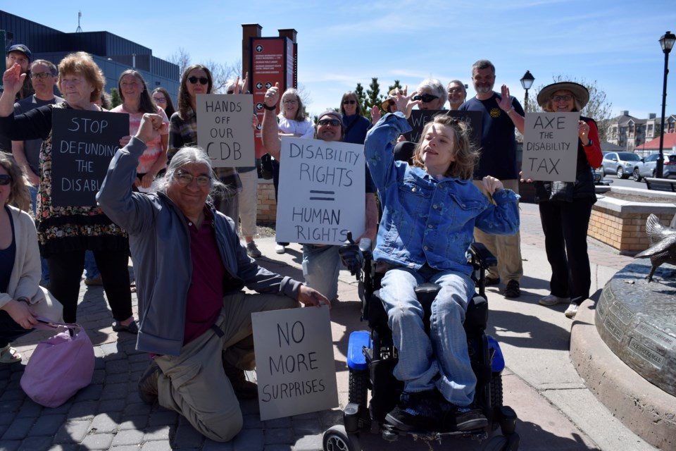Eliza Neven-Pugh, right of centre, and dozens of other protesters demonstrated against the Alberta governments decision to not pass CDB payments on to AISH recipients on May 6 in Cochrane's historic downtown. 