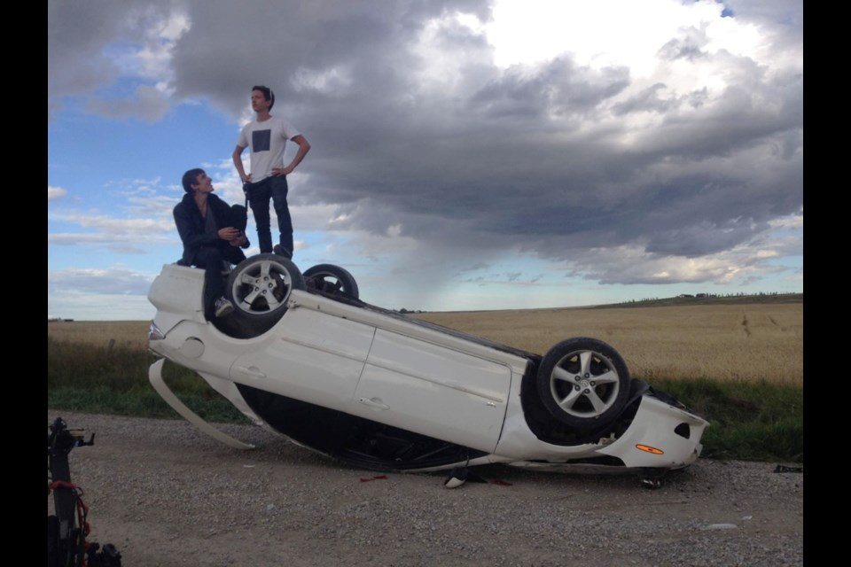 Chris Ball, right, and Kurtis David Harder sit atop a Ball's old car that was flipped for the film Incontrol (2017). Photo submitted.