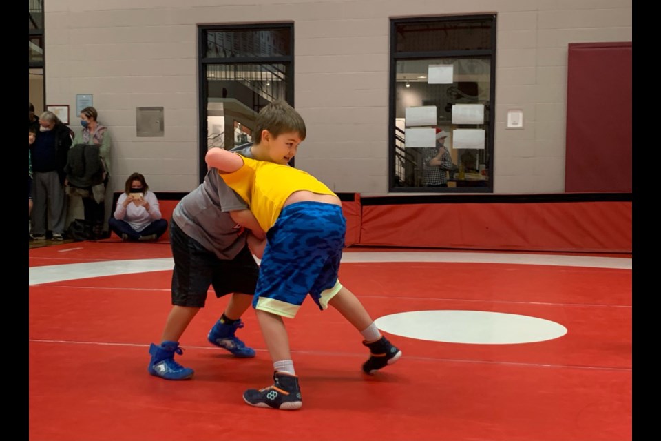 Cowboys Wrestling Club mini Remi Clattenburg, left, grapples with an opponent at the Holiday Tussle tournament in Calgary Dec. 17. (Photo Submitted/April Hooper)