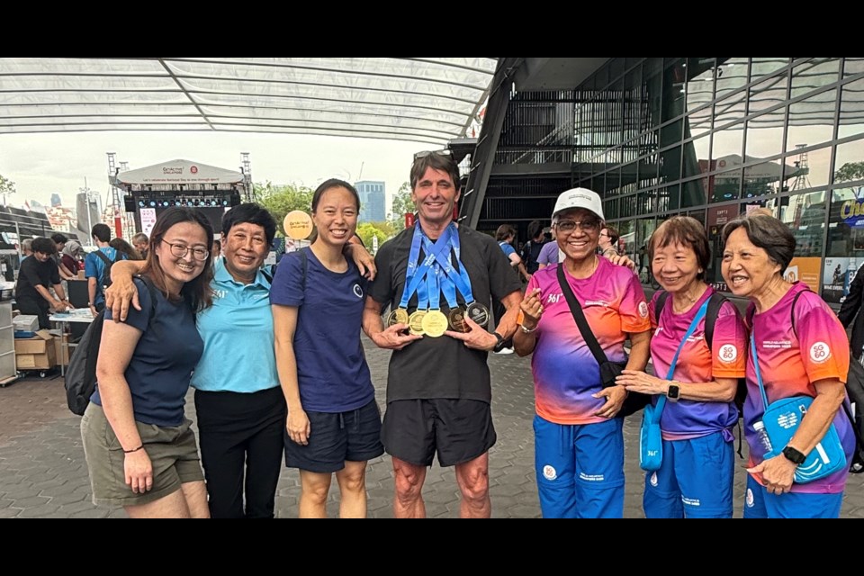 Chris Daniel posing with World Masters Aquatic Championship volunteers in Singapore. 