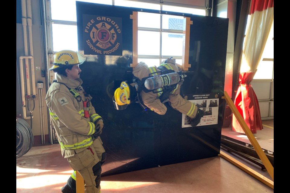  Josh Fahlman uses a simulated second floor window prop and practices hanging out of a window while waiting for rescue.