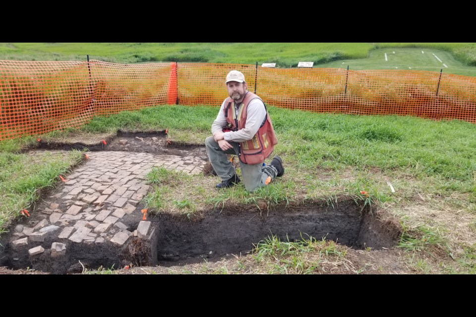 Sean Pickering, senior project archeologist with Bison Historical Services Ltd., kneels beside the floor of a previously unknown building at the Historic Cochrane Ranche. Pickering and his crew of six others are conducting archeological work as part of the design phase for the Highway 1A Highway 22 interchange. 
Photos by Chris Puglia