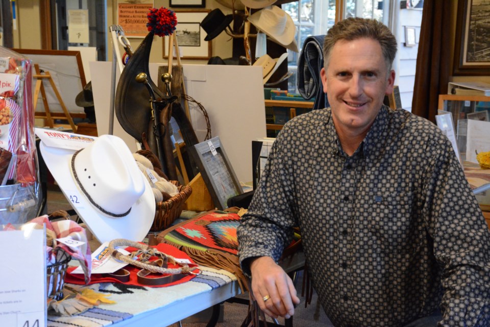 Executive Director of Stockmen's Memorial Foundation, Scott Grattidge smiles in front of an array of goods to be auctioned off in this year's Stockmen's Dinner and Auction on Oct. 30. 