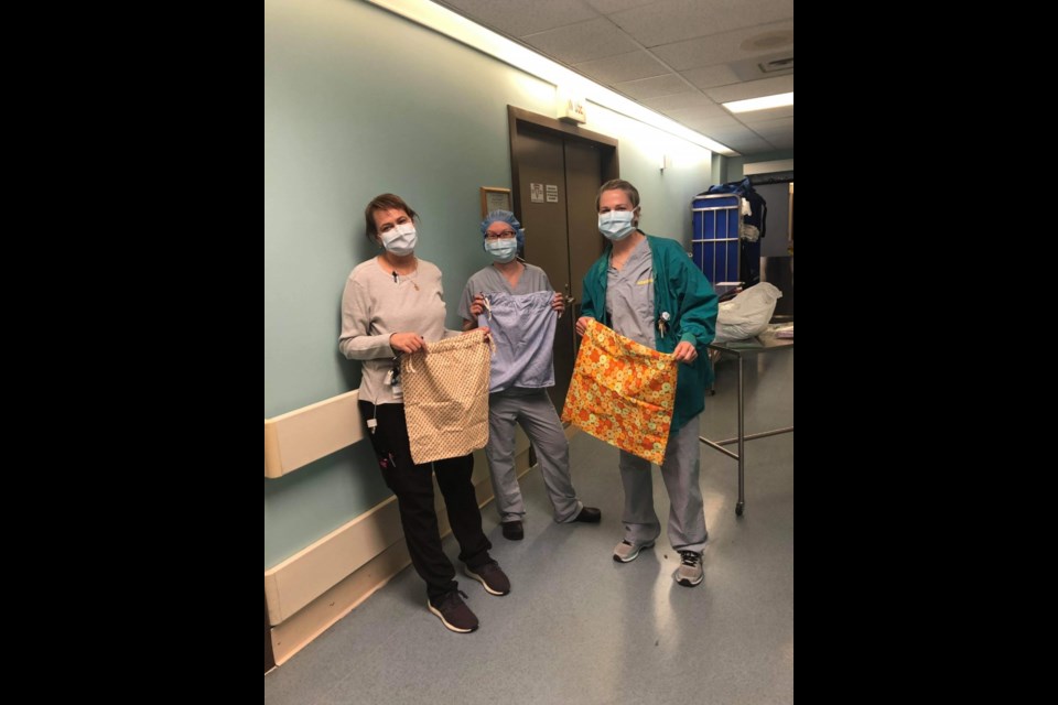 Nina, Alison and Alexis Sickler all show off their scrub bags and those smiles that are hidden behind their face masks. 