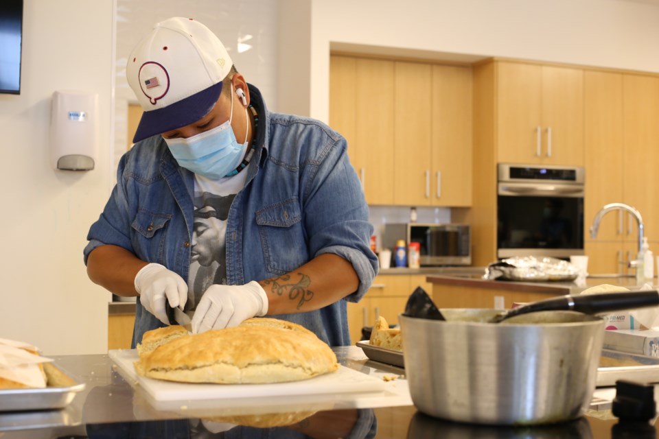 Volunteer Ava Lefthand slices bannock into squares for the attendees of the feast. 