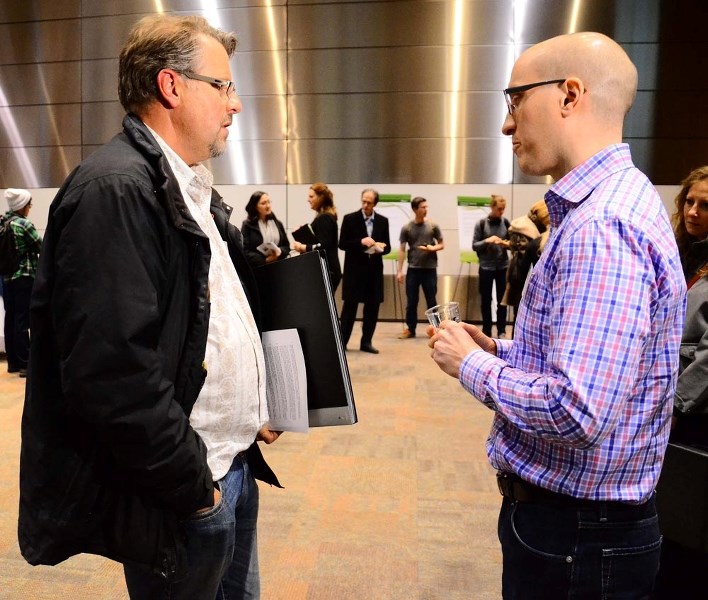 Bragg Creek resident Dick Koetsier, left, speaks with Alberta Environmental and Sustainable Resource Development spokesperson Jason Penner at the province&#8217;s Springbank